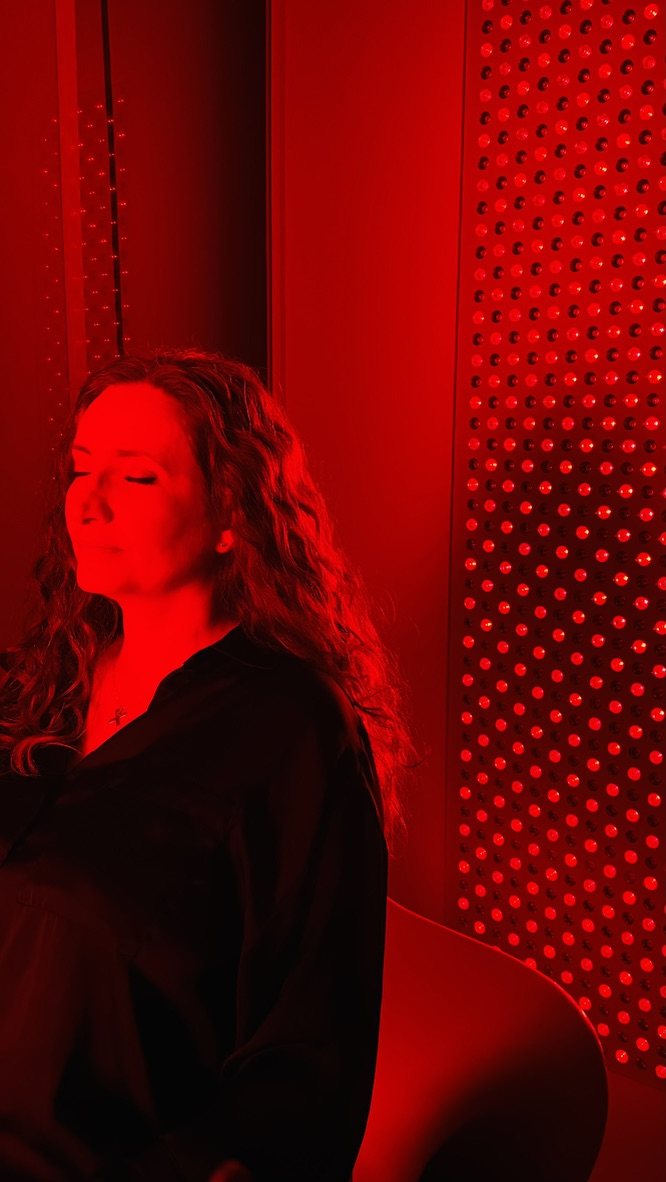 A client relaxing with eyes closed beside the red light panel