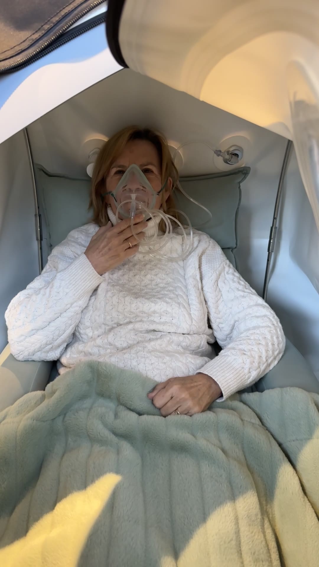A client relaxing inside the chamber with a blanket and soft mask